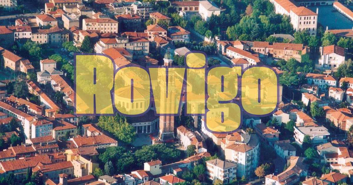 Facciata di casa bolognese con mattoni rossi a vista in prospettiva, finestre archivoltate, intonaco parziale nelle spalle, strada acciottolata