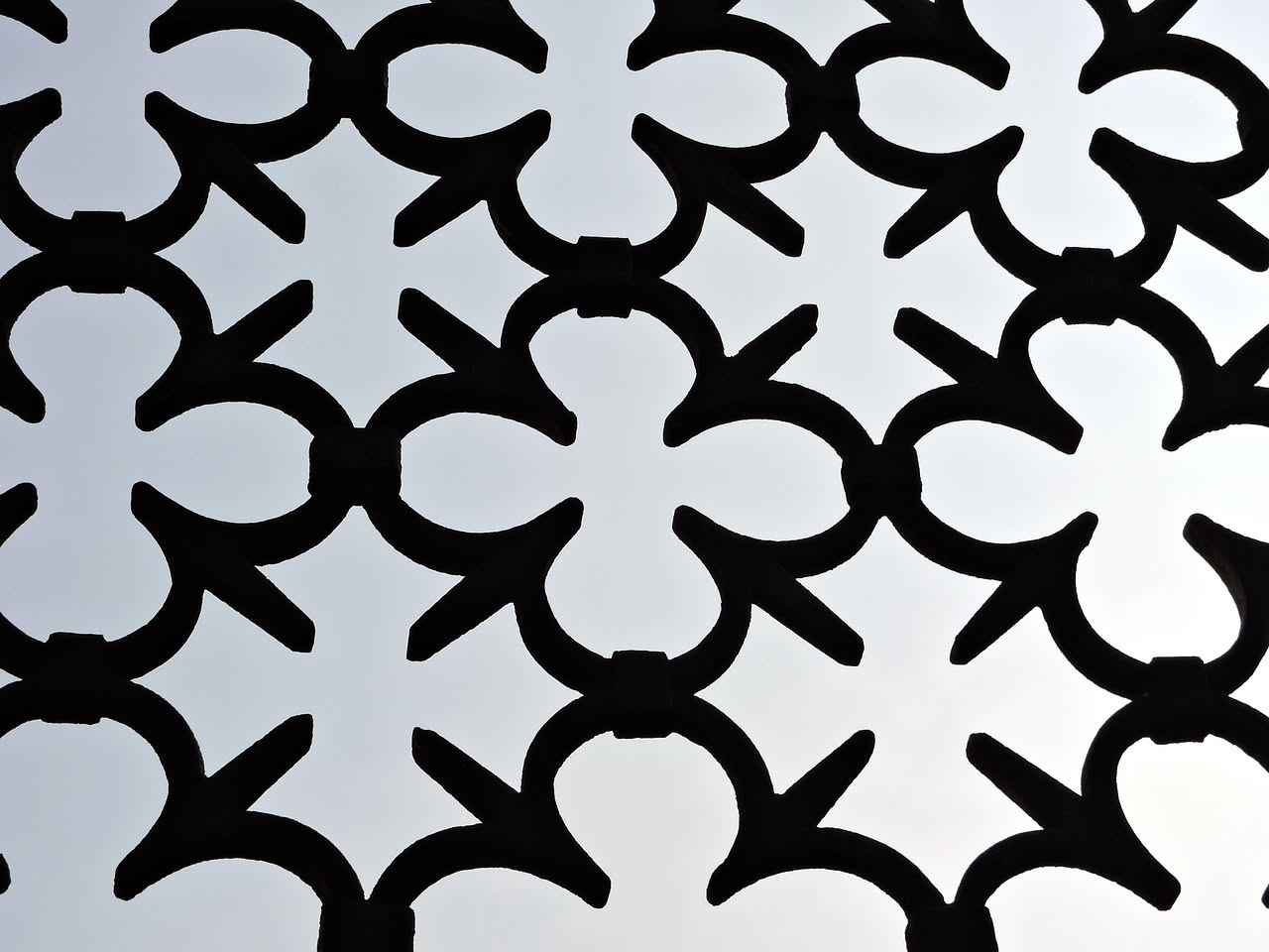 Inferriata decorativa in ferro battuto su una finestra di palazzo barocco siciliano, con motivi a volute floreali e geometrici, foto ripresa al tramonto con ombre lungo la parete
