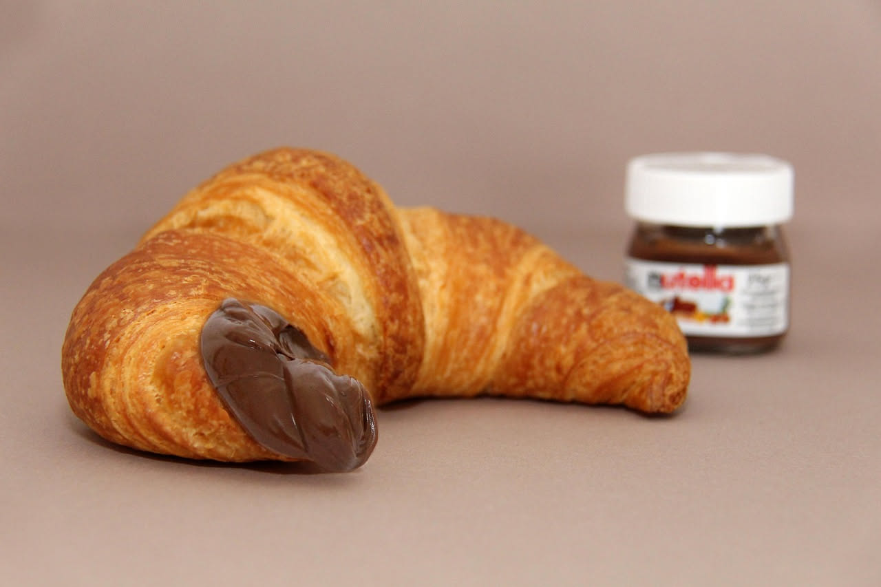 Tre barattoli di crema nocciola a confronto con etichette diverse su sfondo bianco, uno riporta simbolo DOP