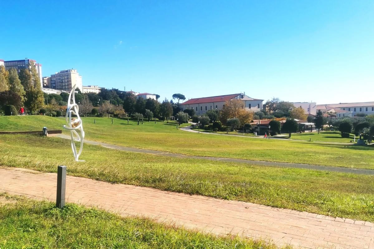 Giardino antico di villa romana con statue di marmo bianco, cipressi, fontane e alberi ad alto fusto che creano zone d'ombra, sullo sfondo i tetti ocra della città