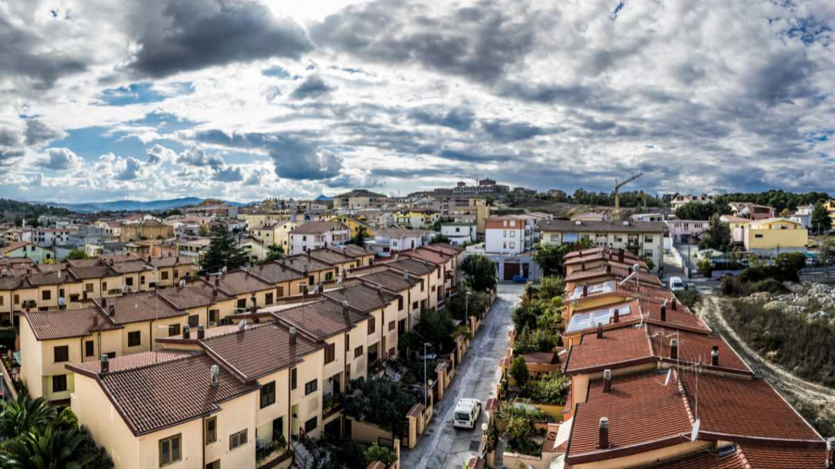 Vecchia cisterna in pietra accanto a moderne grondaie in rame con sistema di raccolta acque su tetto di villa italiana con tegole rosse