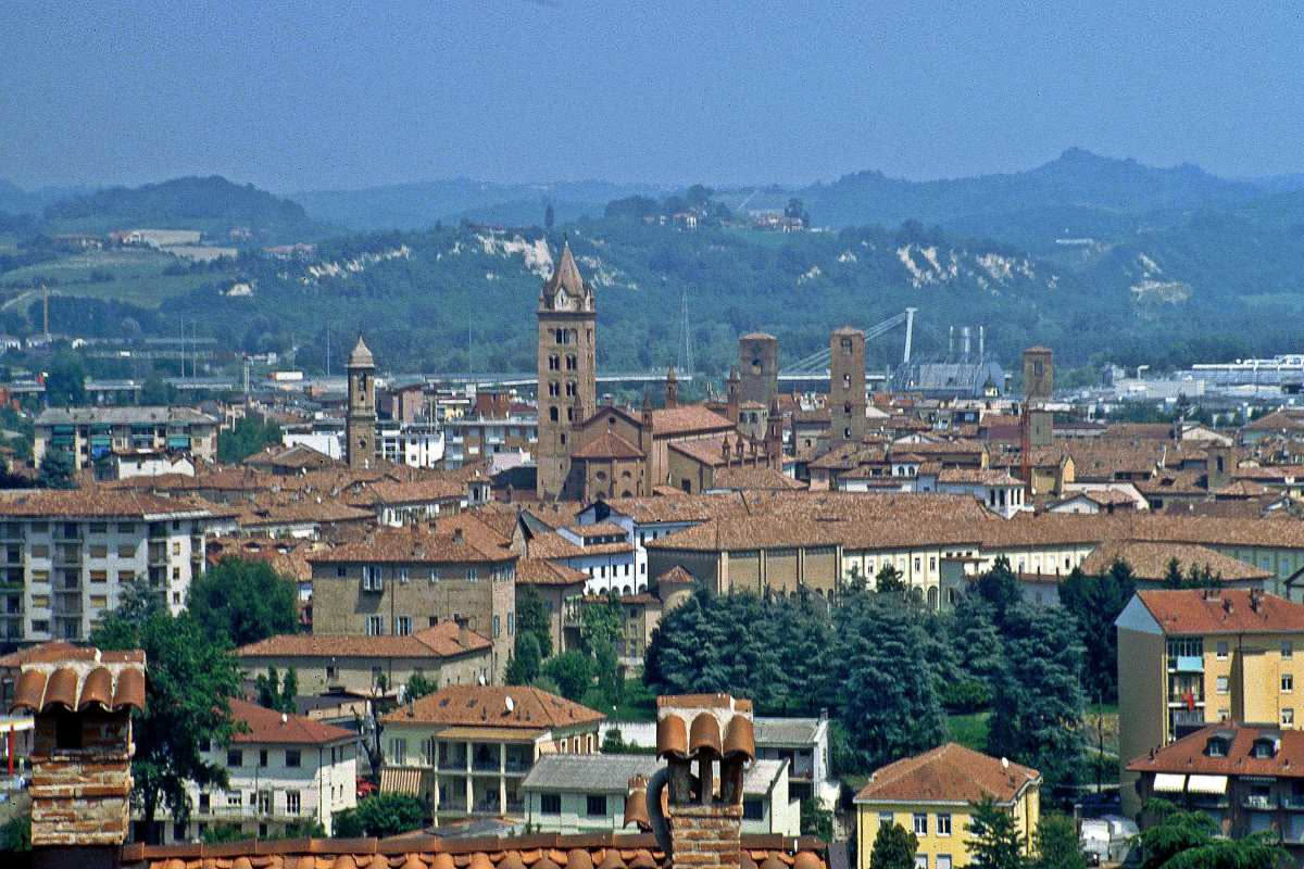Tetto di una basilica medievale con coppi in terracotta rossa, spioventi inclinati e sottotetto in legno massiccio esposto, cielo azzurro sullo sfondo