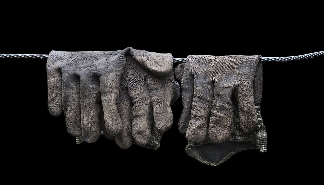 Vecchi guanti colorati di lana e cotone disposti su un tavolo di legno con filo, forbici e altri materiali per il riciclo creativo
