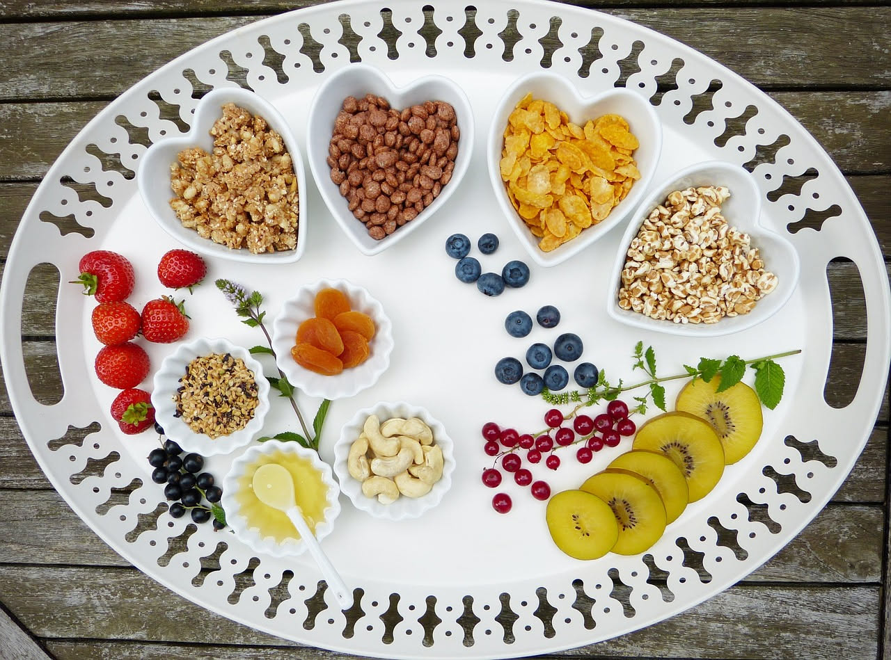 Tavolo con ciotole di legumi, cereali integrali, frutta e verdura fresca colorata su sfondo di legno naturale