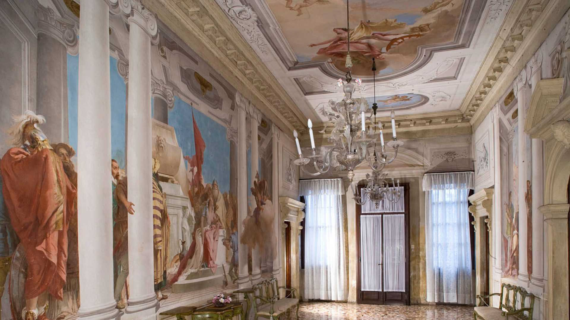 Lampadario di cristallo trasparente appeso al soffitto con gocce di cristallo che riflettono la luce, leggermente ricoperto di polvere prima della pulizia