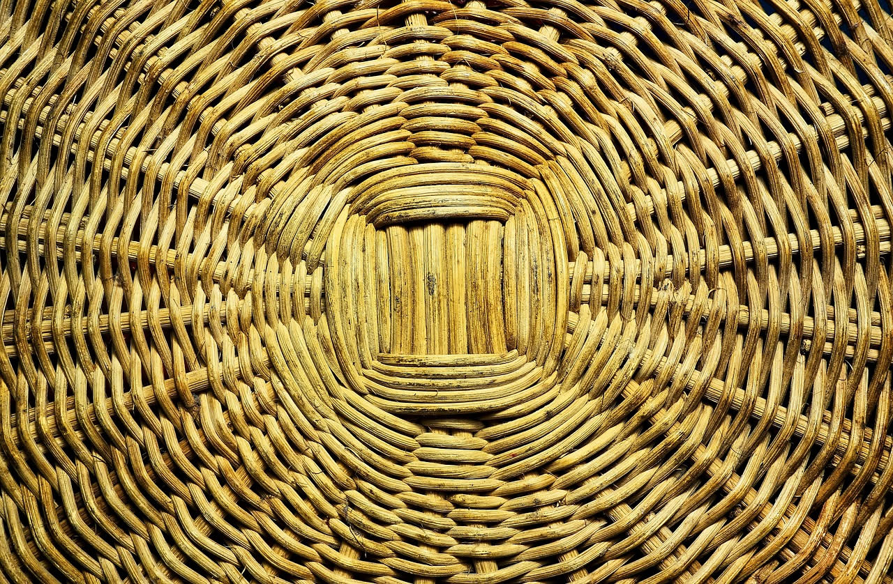 Sedia di paglia intrecciata su sfondo bianco, con fiori secchi accanto e strofinaccio di cotone naturale