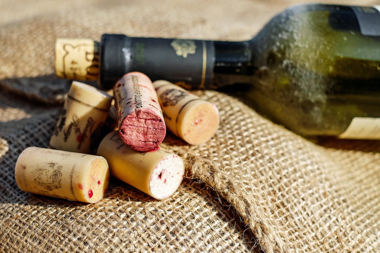 Bicchiere di vino rosso con residui di sedimenti sul fondo, accanto a una bottiglia di vetro e ingredienti naturali come aceto e sale