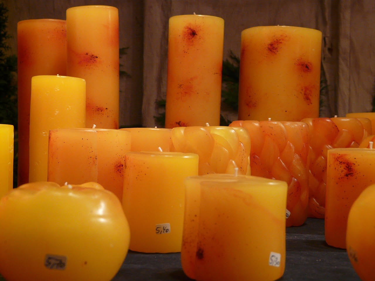 Candela consumata con cera residua in bicchiere di vetro trasparente, accanto a materiali per il riciclaggio e una candela fatta in casa