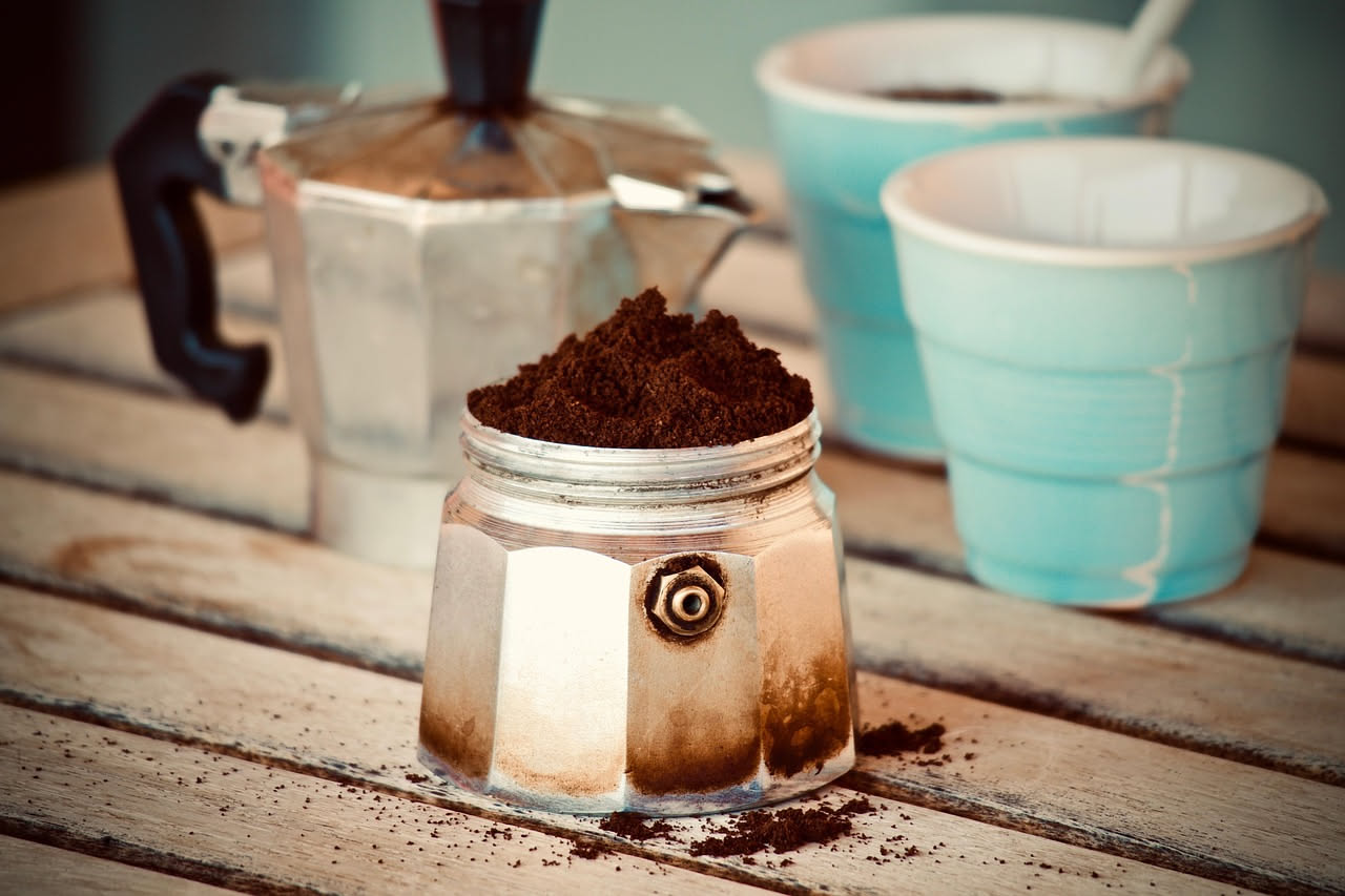 Tazza di ceramica bianca con macchie di caffè marroni sulle pareti interne, accanto a una ciotola di bicarbonato di sodio bianco e mezzo limone giallo