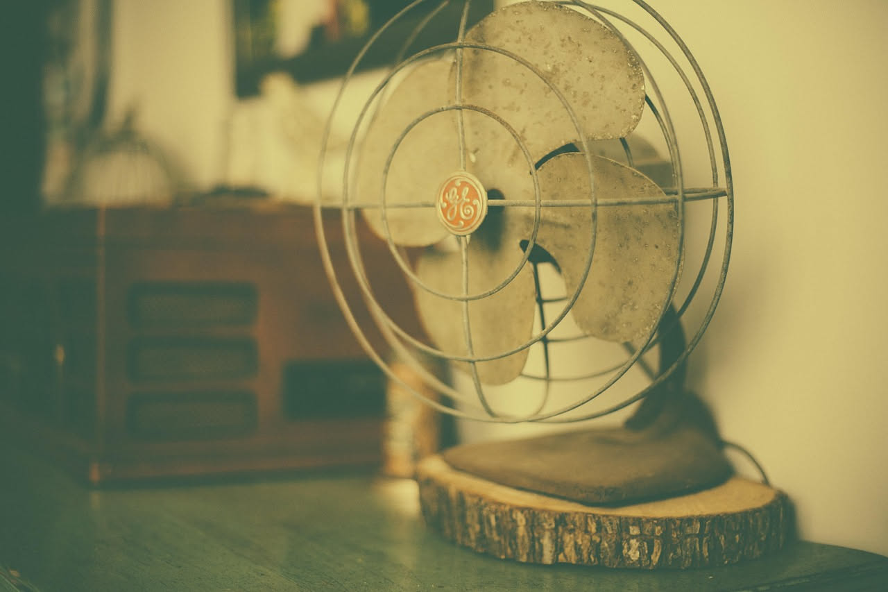 Ventilatore da tavolo bianco completamente smontato con le pale staccate e un panno in microfibra accanto su una superficie di legno