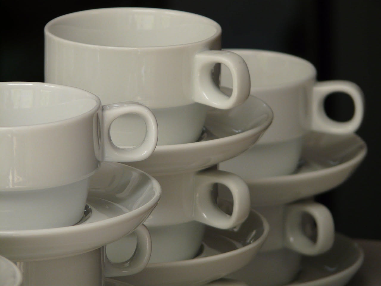 Tazza bianca con macchia di caffè scuro all'interno, bicarbonato bianco in polvere e una spugna naturale su un tavolo di legno chiaro