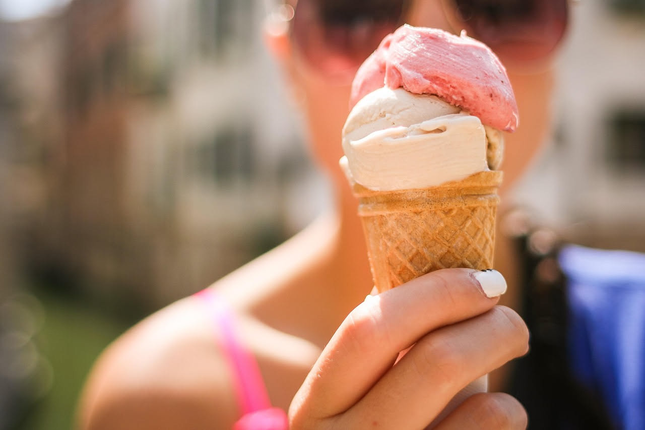 Vestito bianco con macchia rossa di anguria e macchia marrone di gelato al cioccolato su tessuto di cotone, con accanto una ciotola con aceto bianco e un limone tagliato a metà