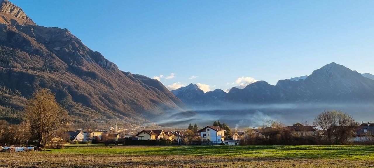 Finestra aperta al mattino presto in una camera da letto soleggiata con una brezza leggera che muove le tende bianche, ambiente luminoso e fresco