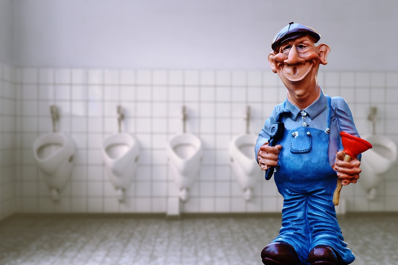 Dettaglio ravvicinato di un wc in ceramica bianca con macchie gialle e marroni di calcare e ossidazione, con uno spazzolone in vimini accanto e una ciotola di bicarbonato bianco