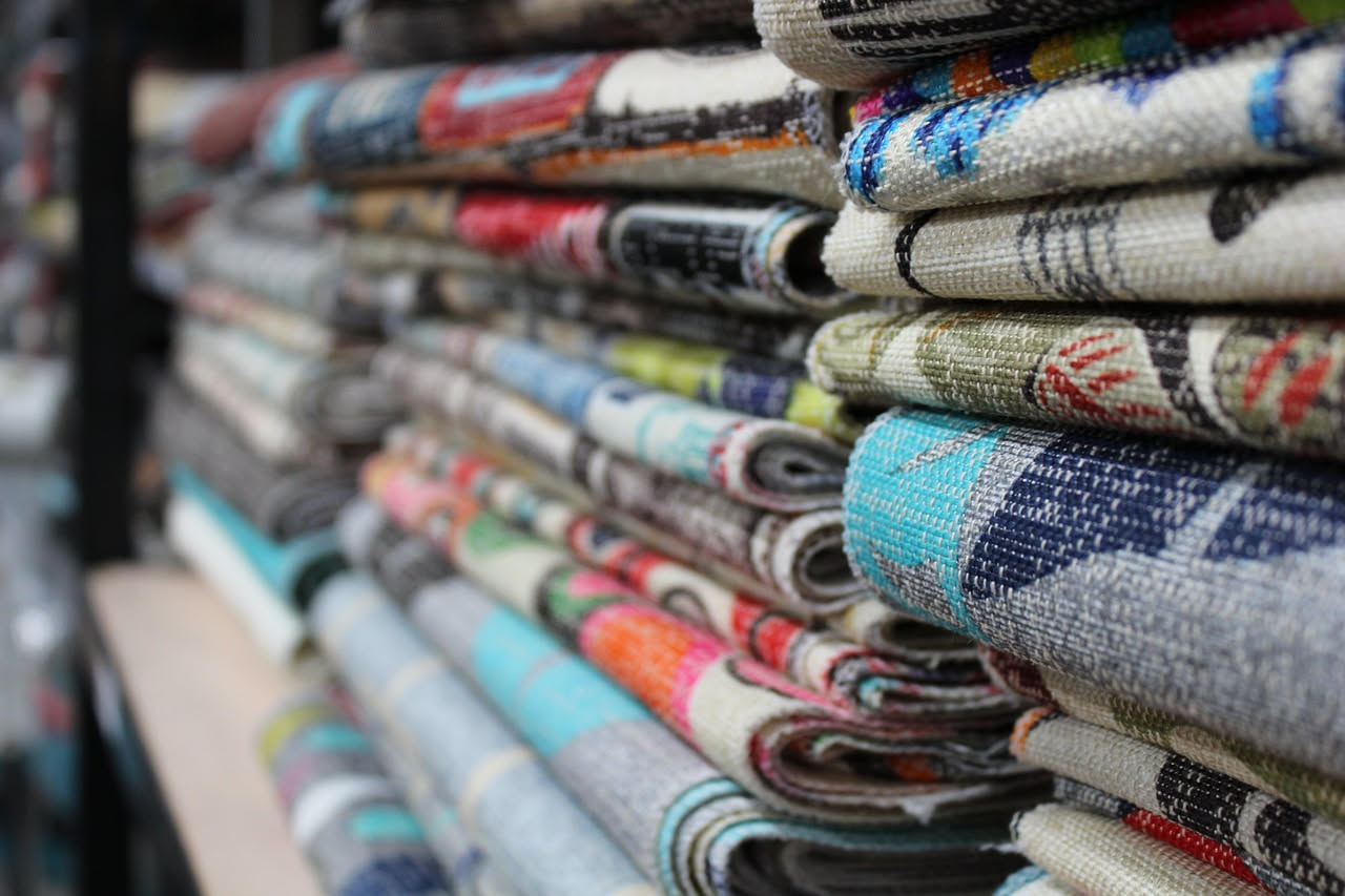Dettaglio ravvicinato del rovescio di un tessuto jacquard multicolore con fili intrecciati irregolarmente e trama visibile, su fondo bianco