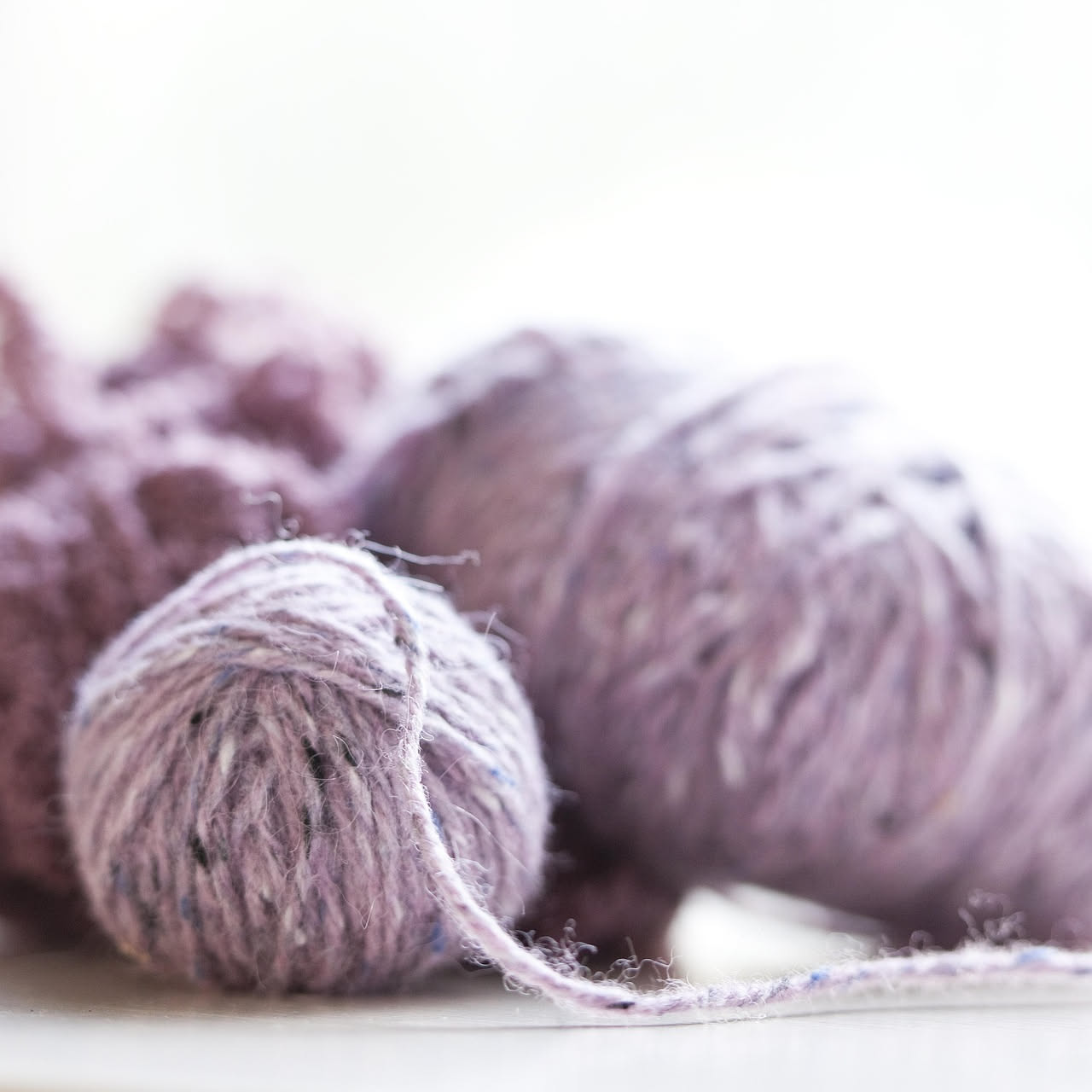 Fibra di lana al microscopio che mostra squame microscopiche sovrapposte e intrecciate, con un colore da bianco a grigio perla su sfondo scuro