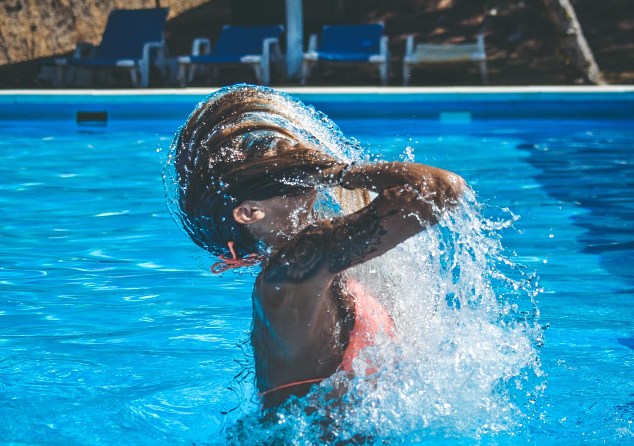 Costume da bagno blu steso su un asciugamano bianco, accanto a una ciotola d'acqua dolce e una spugna morbida