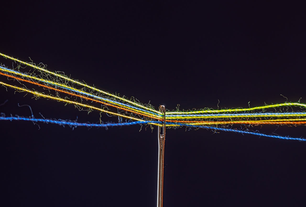 Ingrandimento macroscopico di fibre di lana tinta, con visibili tracce di residui polvérosi sulla superficie e trama compatta delle fibre colorate