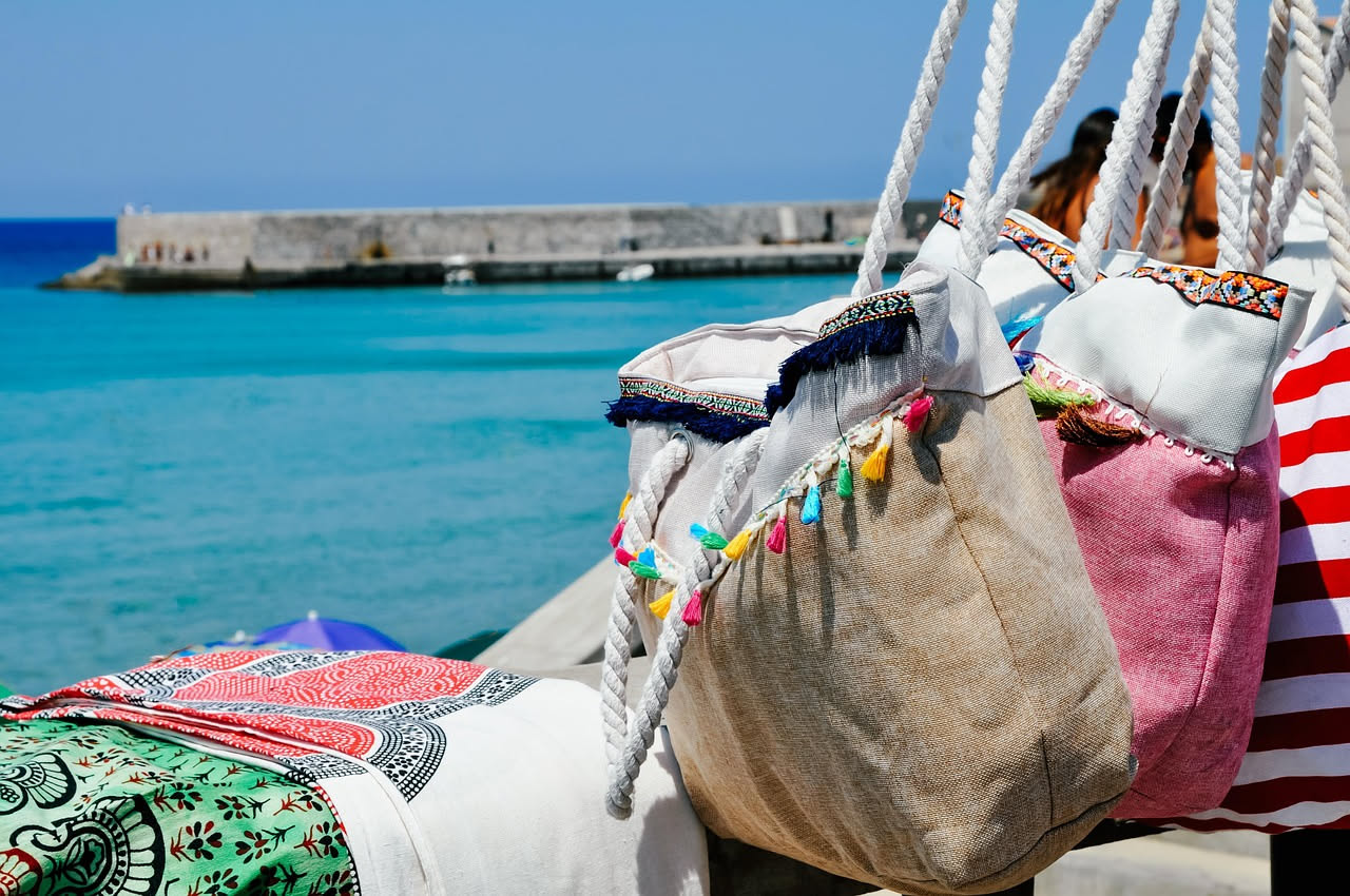 Telo da mare bianco e morbido steso al sole con gocce d'acqua, accanto a una bacinella con sapone e spugna