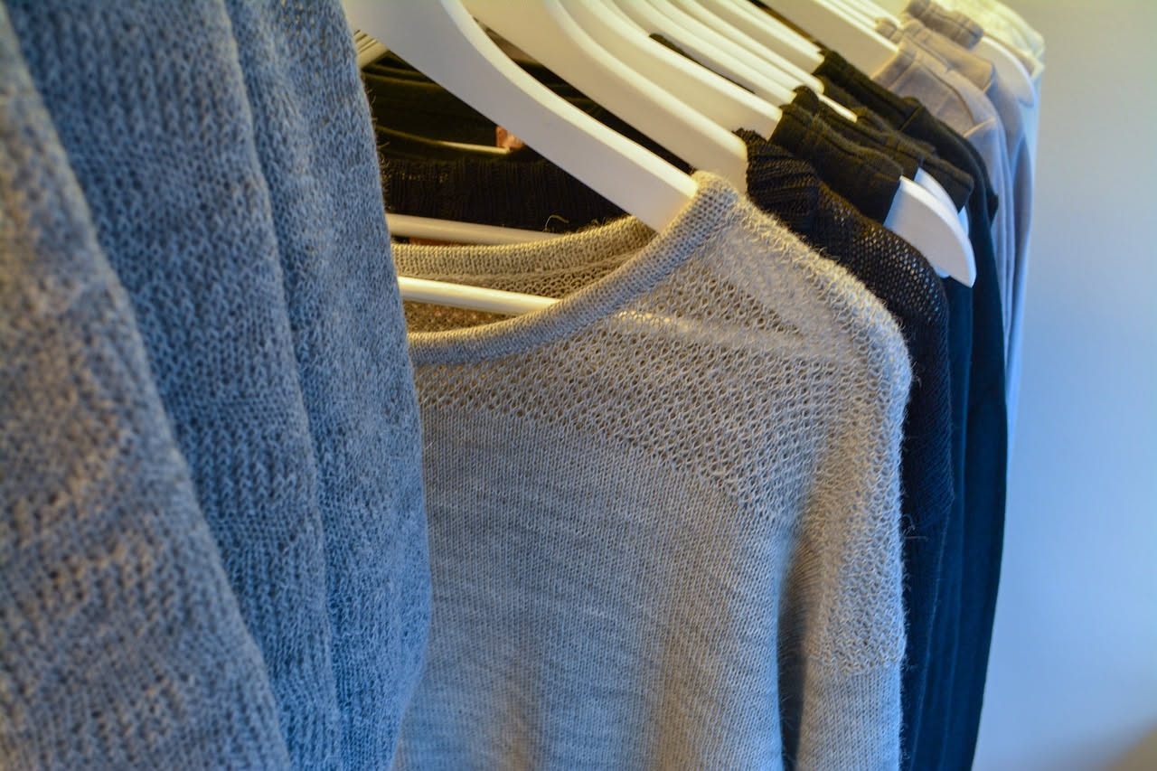 Due maglioni di lana color crema e grigio appoggiati uno accanto all'altro, dettaglio della trama a maglia vista da vicino