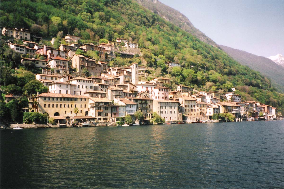 Le case di Gandria affacciate sul lago di Lugano, con le facciate dipinte che si specchiano nell'acqua, le scalinate strette e il campanile romanico della chiesa di San Vigilio.